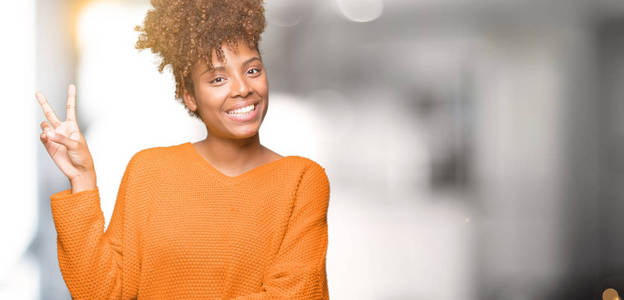 美丽的年轻非洲裔美国妇女在孤立的背景上微笑，快乐的脸对镜头眨眼，做胜利标志。 二号。