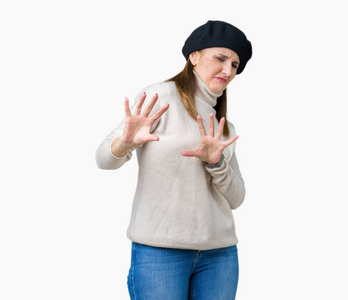 中年成熟的女人穿着冬天的毛衣，在孤立的背景下，厌恶的表情，不高兴和恐惧的做厌恶的脸，因为厌恶的反应。 举起双手。 令人讨厌的概念