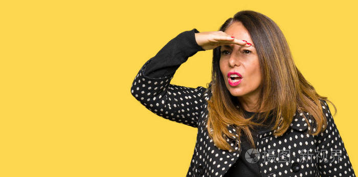 美丽的中年妇女穿着时尚夹克,非常高兴和微笑,用手捂住头看着远方.