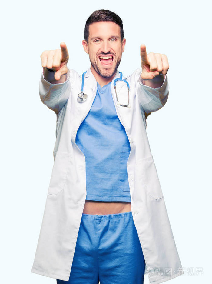 英俊的医生穿着医疗制服，背景与世隔绝，手指指着你和相机，微笑着，积极而愉快