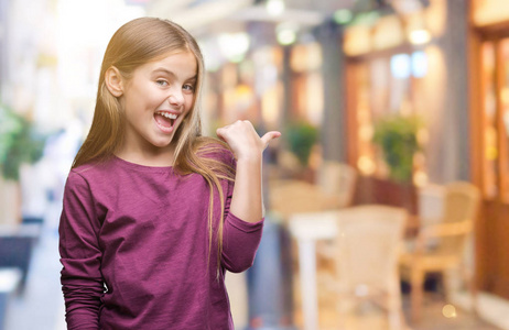 年轻美丽的女孩在孤立的背景上微笑,快乐的脸,看着和指向一边,拇指