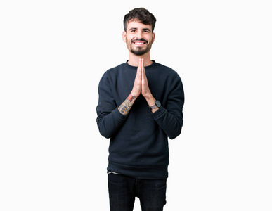 年轻的英俊男子在孤独的背景下祈祷,双手一起请求宽恕,微笑自信.照片
