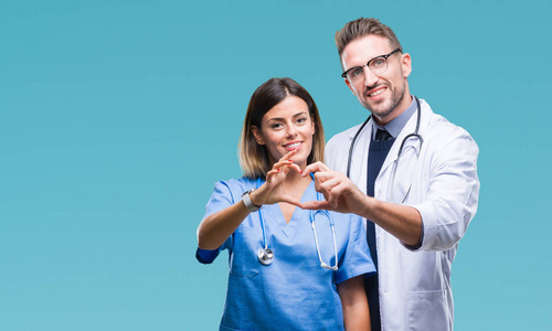 医生显示心脏标志年轻的一对医生和外科医生在孤立的背景上微笑,在爱