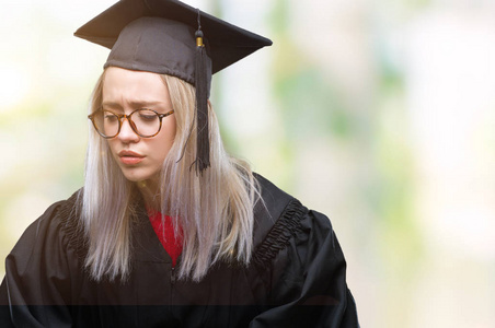 年轻的金发女人穿着研究生制服，在孤立的背景上，手放在肚子上，因为恶心痛苦的疾病感觉不舒服。 疼痛的概念。