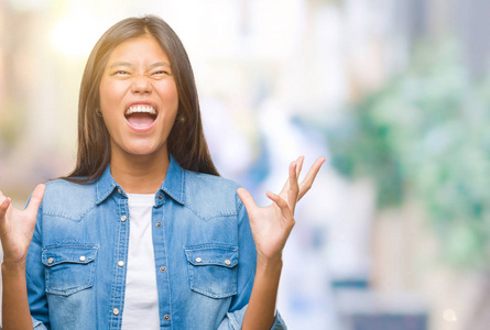 年轻的亚洲女人在孤立的背景下疯狂和疯狂地大喊大叫，带着咄咄逼人的表情和手臂抬起。 挫折概念。