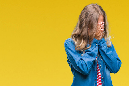 美丽的年轻金发女人在孤立的背景上,悲伤的表情覆盖着脸,双手哭泣.