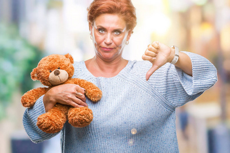 高白种人妇女抱着泰迪熊在孤立的背景下愤怒的脸消极的迹象显示不喜欢拇指向下拒绝的概念