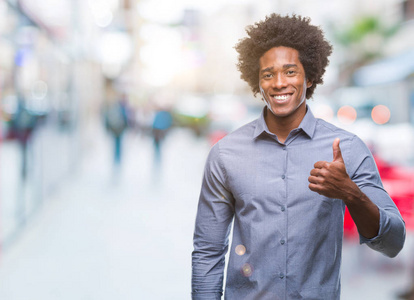 美国黑人男子在孤立的背景下，用手做快乐的竖起大拇指的手势。 赞许的表情看着相机，显示出成功。