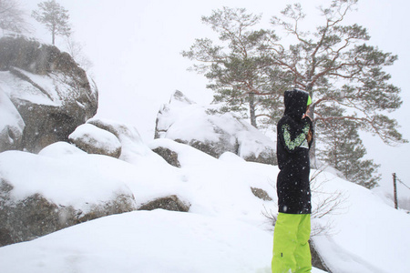 冬季森林。 那个女孩在岩石上。 长长的黑色紧身滑雪绿裤。 下着雪的多布什岩石乌克兰