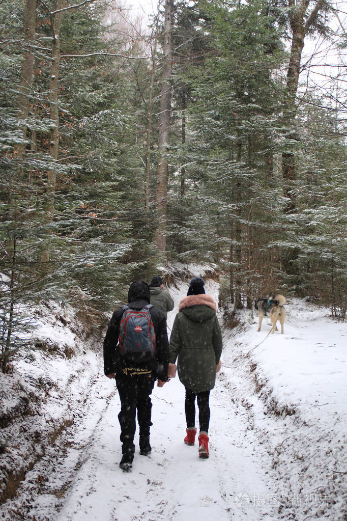冬季森林走在男孩和女孩的陪伴下在山上徒步旅行冬季雪