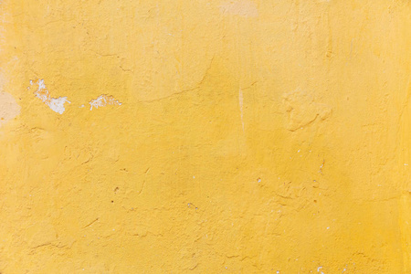 明亮的黄色油漆墙。 风化和褪色的纹理背景。 住宅建筑的外立面