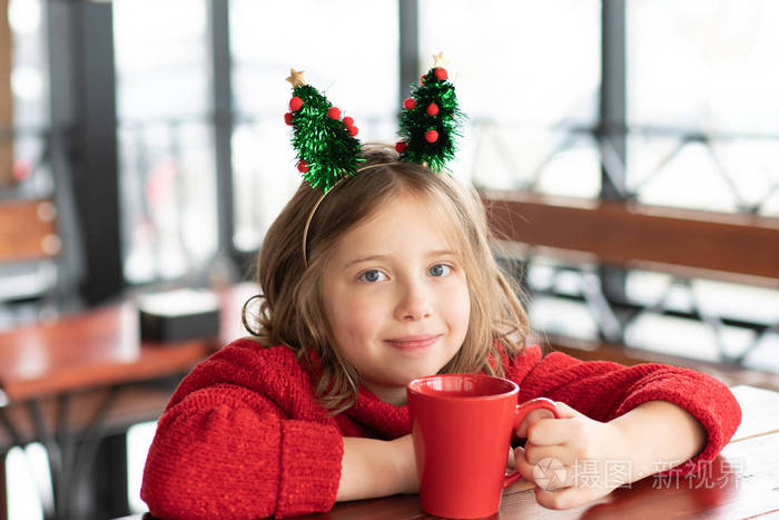 圣诞节一个小女孩坐在咖啡馆里的画像