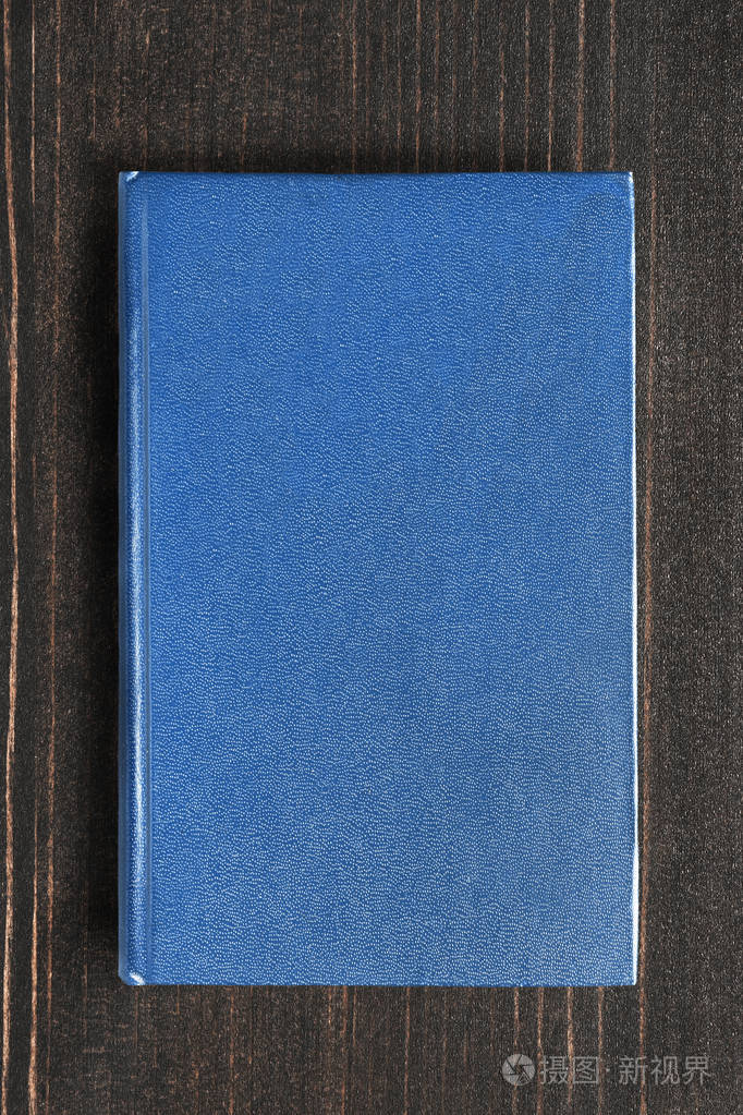 带蓝色空白封面的书,深棕色木制背景