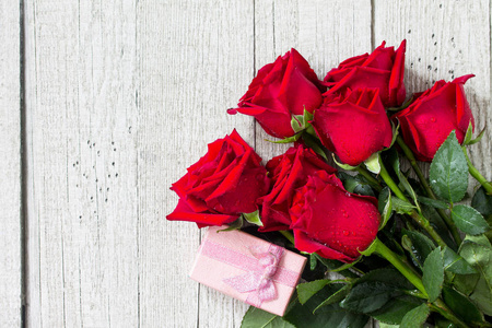 婚礼或情人节母亲日卡。 美丽盛开的红玫瑰和木板上的礼品盒。 顶部视图平躺背景。 复制空间。