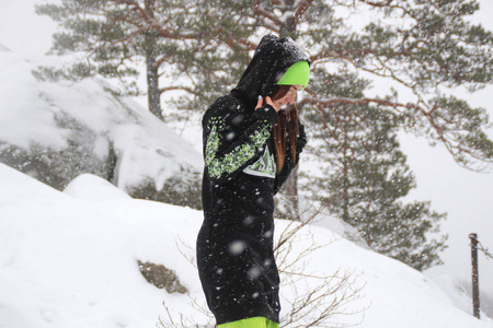 冬季森林。 那个女孩在岩石上。 长长的黑色紧身滑雪绿裤。 下着雪的多布什岩石乌克兰