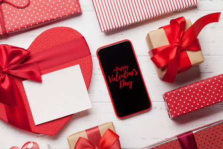 s day greeting card with heart gift boxes and smartphone on wood