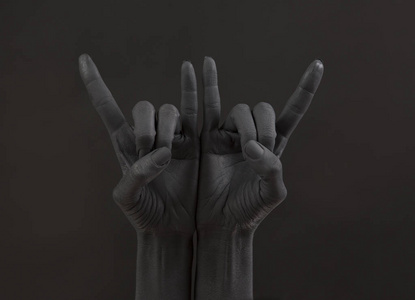 山羊在黑暗的背景上做手势.黑手做摇滚符号.在摇滚音乐会上举起手来.