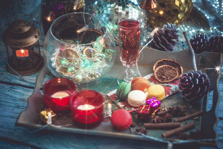 圣诞节仍然生活与一杯葡萄酒，马卡龙，蜡烛，干果和香料。 照片着色，并与Vignette与灯和波克。