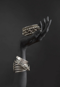 s hand with Silver jewelry. Oriental Bracelets on a black painte