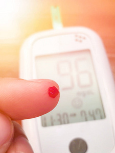用血滴接近手指，测试条纹医学，糖尿病，血糖，保健和人们的概念