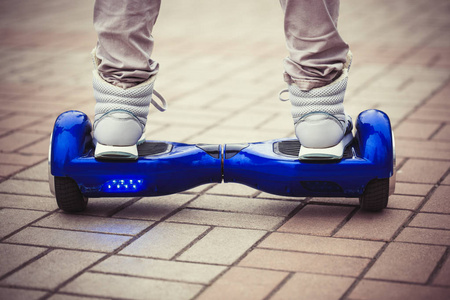 人骑现代蓝色电动迷你赛格威或悬停板滑板车在户外。 受欢迎的新城市交通，既方便又有趣，不会对大气造成空气污染