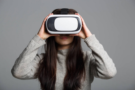 使用新的增强现实眼镜用于移动游戏玩家应用程序的漂亮女孩工作室肖像。使用带有创新3D VR耳机的移动游戏应用程序。Trendy虚拟