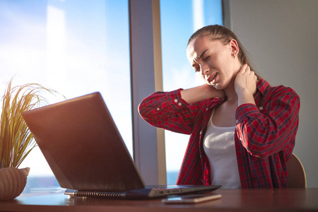 腰背肌疼痛年轻女子在电脑上工作了很长时间后,感到颈椎不舒服,按摩