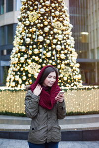 一个年轻的黑发女孩在户外摆着装饰得鲜艳的圣诞树