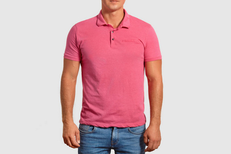 裁剪镜头的年轻肌肉男子穿休闲粉红色T恤与空白空间，为您的广告牛仔裤摆在白色工作室墙广告服装。 人们的时尚和风格观念