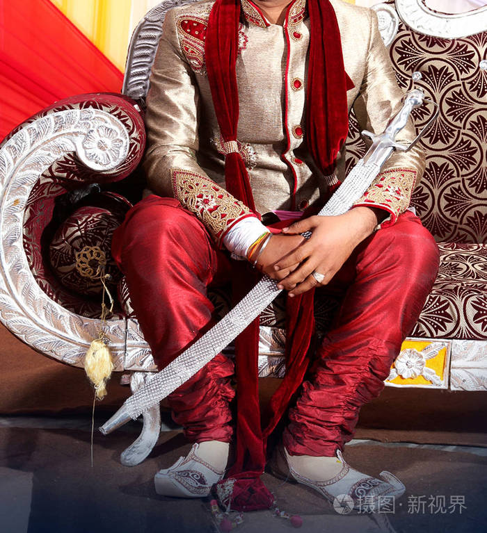 印度新郎坐在沙发上的婚礼舞台上