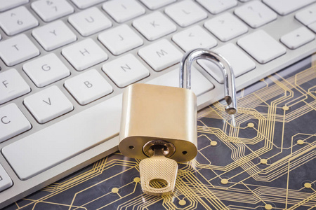 解锁黄金金属挂锁与钥匙在现代白色键盘塑料电子电路板的背景。 数字数据加密在线密码网络安全信息隐私概念。