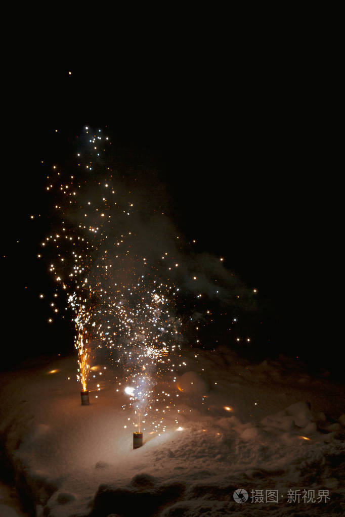 明亮多彩的五彩烟火喷泉在夜间的雪地里