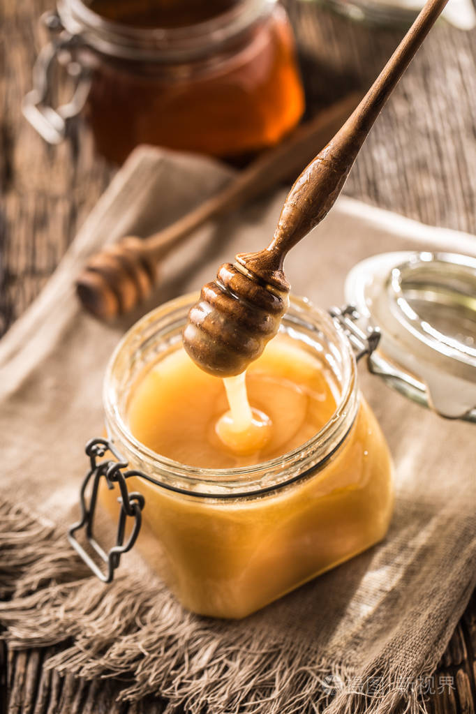 蜂蜜在罐子里迪珀在乡村橡木桌上