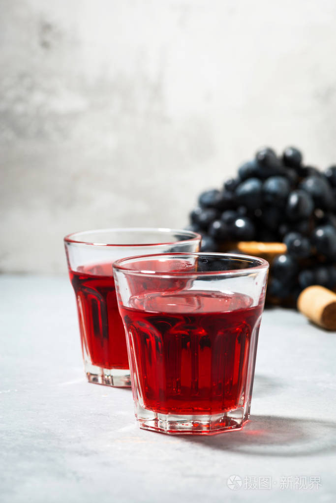 灰色桌子上的两杯红葡萄酒垂直特写