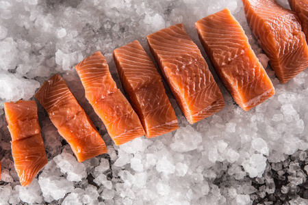 鲑鱼鱼片分在冰上和空的厨房板的顶部。