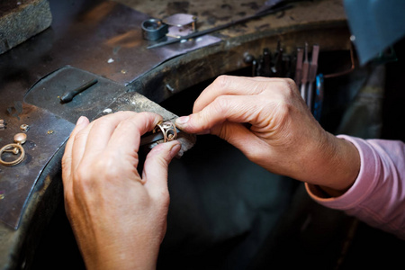 珠宝商在正宗珠宝作坊的旧工作台上用一个金戒指