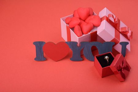 礼品盒。红色背景上的粉红色盒子, 红色的心。题词我爱你。情人节的背景