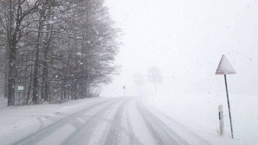 大雪纷飞的冬季道路在冰封的森林中。 寒冷天气暴风雪能见度差。