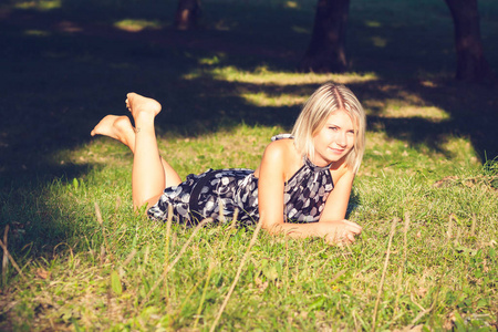 花园里坐在草地上的时髦年轻金发女人的肖像。