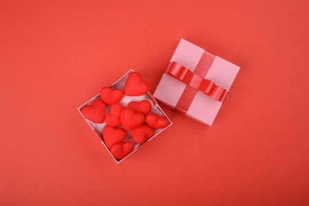 礼品盒。红色背景上的粉红色盒子, 红色的心。情人节的背景