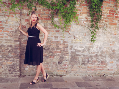 意大利威尼斯阳光明媚的街道上穿着黑色裙子的女人