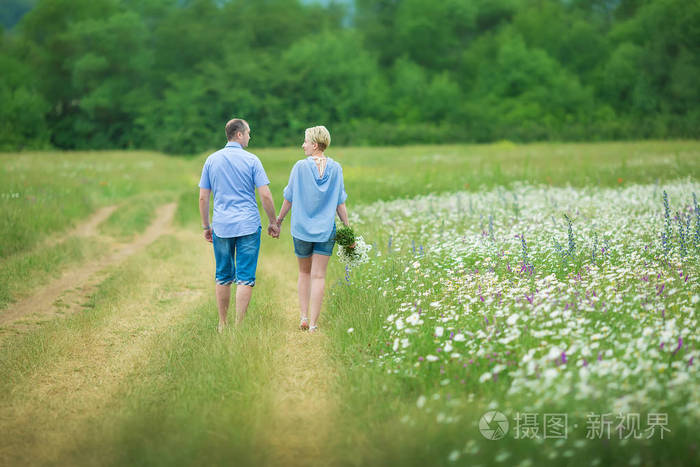 浪漫的情侣在温暖的田野里拥抱呼吸着新鲜的空气,开着几天的花