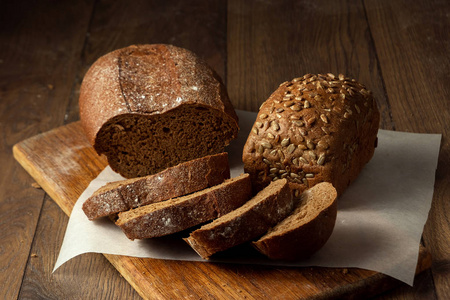 创意背景新鲜烘焙切片黑麦面包在木切割板上平躺复制空间。 新鲜糕点黑面包的概念。