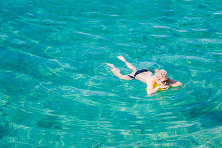 鸟瞰年轻的金发女子游泳在透明的绿松石海。 苗条女士在假期放松的最高景观。