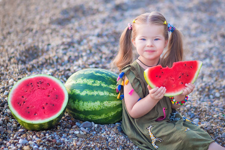 女孩在海滩上吃西瓜，夏天在海边享受美丽的一天。