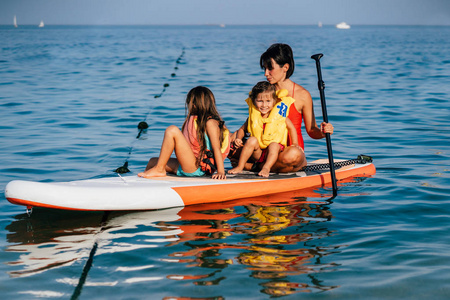 母亲带着两个女儿站在划桨板上