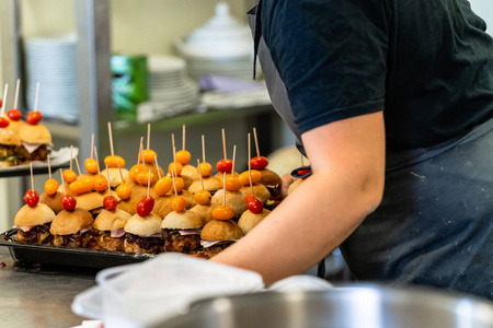 在前景上德国汉堡举行女厨师把汉堡的配料放在切片面包上,摊在桌子上