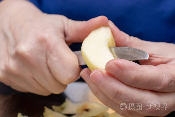 雌性手用刀子从黄色苹果上剥离皮肤。