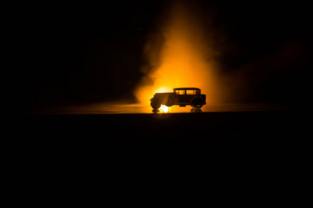 老式汽车的轮廓在黑暗的雾色调背景与发光的灯光在微光。 选择性聚焦