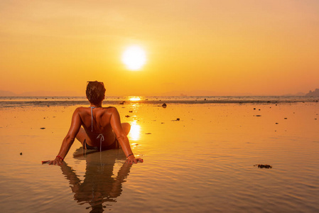 日落时海滩上一位年轻健康的女人的剪影